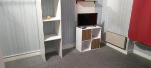 a room with a tv on a stand with a shelf at Appartement 1 in Saint-Germain-Laprade