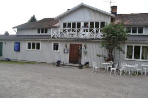 a white house with a balcony with tables and chairs at Berggårdens Gästgiveri in Gnarp