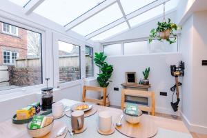 a living room with a table and two windows at Foden's House by YourStays - 2 Bedroom Cottage in Sandbach with gorgeous dining room extension, High end finish in Sandbach