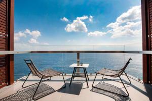 two chairs and a table on a balcony with the ocean at Aquila Elounda Village Resort, Suites & Spa in Elounda