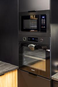 una cucina con forno a microonde e forno in acciaio inossidabile di Apartament Larice VIP - sauna, balia, basen a Świeradów-Zdrój