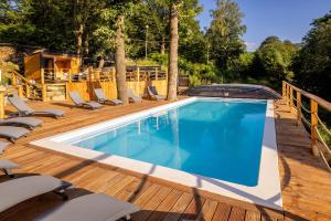 una piscina su un ponte di legno con sedie intorno di Apartament Larice VIP - sauna, balia, basen a Świeradów-Zdrój