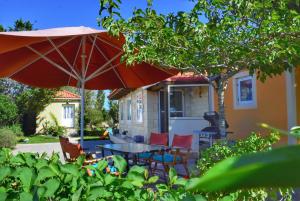 a patio with a table and chairs and an umbrella at Pear Tree Cottage in Lixouri