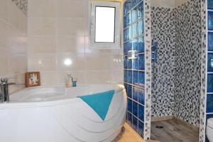 a bathroom with a tub and a shower with blue tiles at Pear Tree Cottage in Lixouri +19 photos