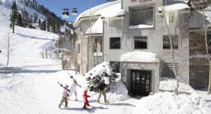 a group of people standing in the snow in front of a building at Palisades Tahoe Lodge Rentals Studio Loft #308 in Olympic Valley