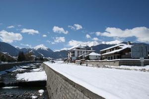 a river with snow on the ground next to houses at Luxury Apartment 5 Mins from Slopes Parking in Bansko