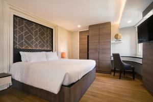 a bedroom with a bed and a desk and a television at Aspira Suites Sukhumvit 20 in Bangkok