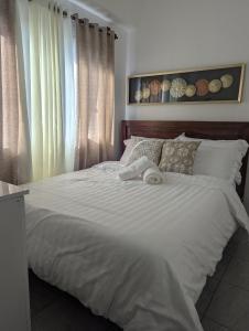 Un dormitorio con una cama grande con sábanas blancas. en Casa de Ara, en Baguio