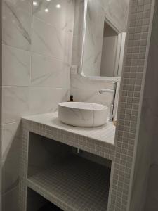 Un baño blanco con lavabo y espejo. en Confortable 2 pièces entre Menton et Monaco avec parking privé, en Roquebrune-Cap-Martin
