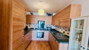 a kitchen with wooden cabinets and black counter tops at Luxury 1 bed flat at WembleyPark in London +24 photos