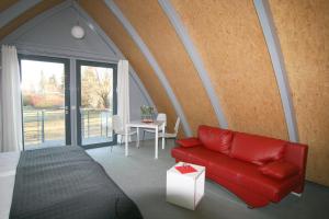 a bedroom with a red couch and a table at Gästehaus am Lausitzring in Poley