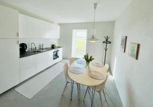 a white kitchen with a table and chairs at Solhögs Gård nr 3 in Hammenhög