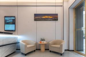 a living room with two chairs and a tv on the wall at Shanghai Manhua Hotel-Provides free shuttle service to Disneyland in Shanghai