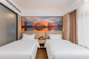 two beds in a room with a painting on the wall at Shanghai Manhua Hotel-Provides free shuttle service to Disneyland in Shanghai