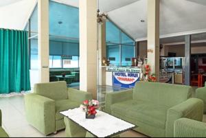 a lobby with two couches and a table with flowers at Hotel krui syariah in Krui