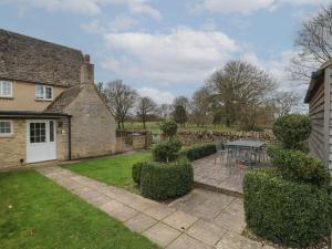 a house with a patio and a table in the yard at Stable Cottage in Lechlade