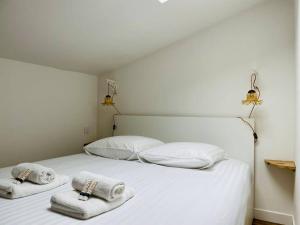 a bedroom with a white bed with towels on it at Le Boudoir de Thais in La Rochelle