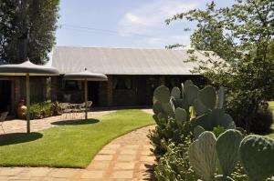 a garden with a house with a table and an umbrella at Grincourt B&B- with No Load shedding in Polokwane
