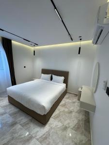 a white bedroom with a bed and a table at جود ان للشقق الفندقية in Aţ Ţunḑubāwī
