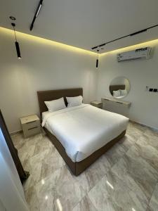 a bedroom with a white bed and a mirror at جود ان للشقق الفندقية in Aţ Ţunḑubāwī
