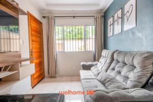 a living room with a couch and a large window at Casa em Itanhaém com piscina a 5 minutos da praia in Itanhaém