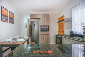 a kitchen with a stainless steel refrigerator and a table at Casa em Itanhaém com piscina a 5 minutos da praia in Itanhaém