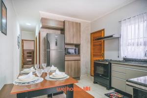 a kitchen with a table with plates and wine glasses at Casa em Itanhaém com piscina a 5 minutos da praia in Itanhaém
