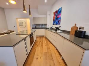 a large kitchen with white cabinets and a wooden floor at Luxury Altrincham Flat by City SuperHost in Altrincham