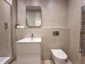 a bathroom with a toilet and a sink and a mirror at Luxury Altrincham Flat by City SuperHost in Altrincham
