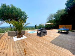 une terrasse en bois avec une piscine, une table et des chaises dans l'établissement Villa Monbazillac, vue exceptionnelle, piscine, jacuzzi 10-12 pax, à Monbazillac