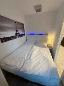 a bedroom with a white bed with a picture on the wall at Neu renovierte Whg nähe Wasserbahnhof und Krankenhaus mit Aufzug Große Küche in Mülheim an der Ruhr