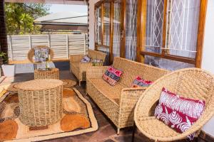 een patio met rieten stoelen en tafels op een veranda bij Casa Linda in Harare