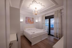 a white bedroom with a bed and a chandelier at Luxury Apartment in Sarandë