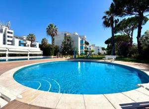 a swimming pool in a resort with palm trees at Appartement Algarve,Quarteira Vilamoura Lago Azul in Vilamoura