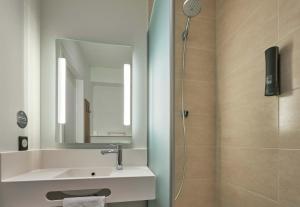 a bathroom with a sink and a shower with a mirror at B&B HOTEL Ouistreham in Ouistreham