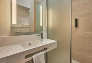 a white bathroom with a sink and a mirror at B&B HOTEL Ouistreham in Ouistreham
