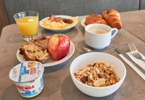 a table with plates of breakfast foods and a glass of orange juice at B&B HOTEL Ouistreham in Ouistreham