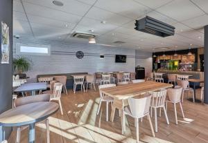 a restaurant with tables and chairs in a room at B&B HOTEL Ouistreham in Ouistreham