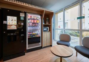 a room with a refrigerator and two chairs and a table at B&B HOTEL Ouistreham in Ouistreham