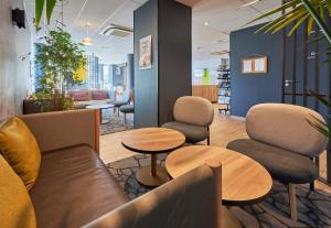 a waiting room with couches and chairs and tables at B&B HOTEL Ouistreham in Ouistreham