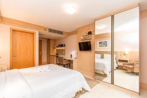 a bedroom with a white bed and a mirror at BSB STAY Flats Particulares - Cullinan SHN in Brasilia