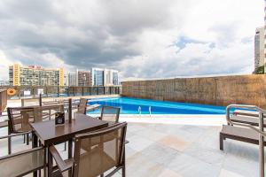 a patio with tables and chairs next to a swimming pool at BSB STAY Flats Particulares - Cullinan SHN in Brasilia