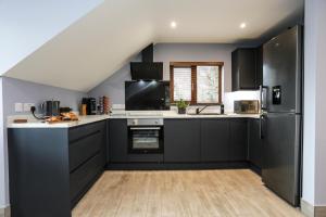 a kitchen with black cabinets and a refrigerator at Oak View Lodge - Deluxe Master Studio near Ipswich & Woodbridge in Playford