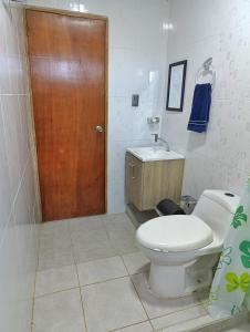 a bathroom with a toilet and a wooden door at Apartamento sereno, cerca al mar in El Porvenir