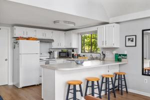 a kitchen with white cabinets and bar stools at Mountain Views w Fire Pit Deck Grill & Amenities in Hedgesville