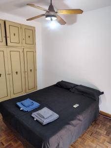 a bedroom with a black bed with a ceiling fan at Departamento céntrico in Concepción del Uruguay