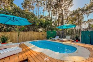 a swimming pool with two umbrellas on a wooden deck at SAGRADAS de LA PALOMA in La Paloma