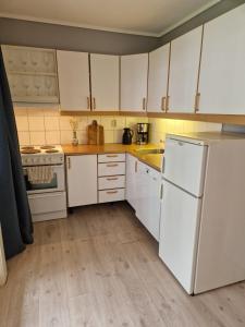 a kitchen with white cabinets and a white refrigerator at Leilighet rett ved stranden in Mandal