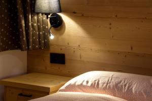 una camera da letto con una parete in legno, un letto e una lampada di Apartments Alla Caminada ad Alleghe