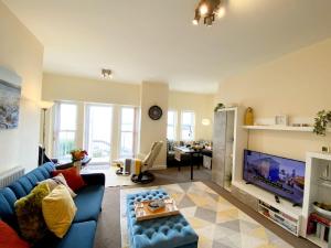 a living room with a blue couch and a tv at No1 Marina Court - Wow Sea View Apartment in Torquay